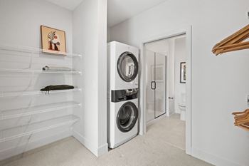 A white laundry room with a washer and dryer built into the wall.